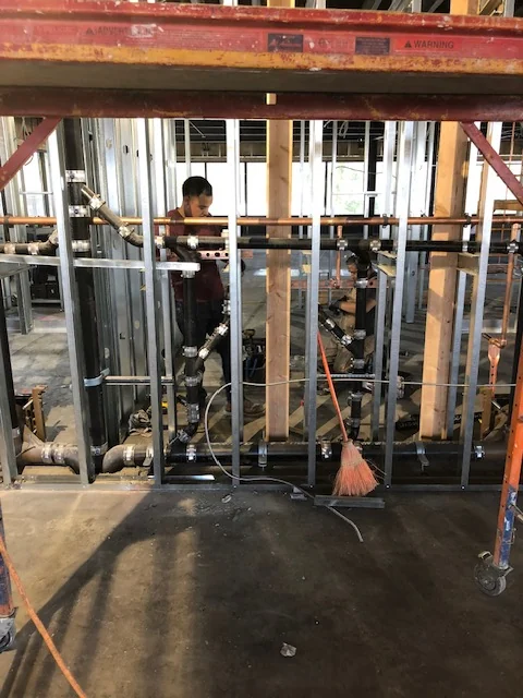 Commercial plumbing rough-in with cast-iron waste and copper supply